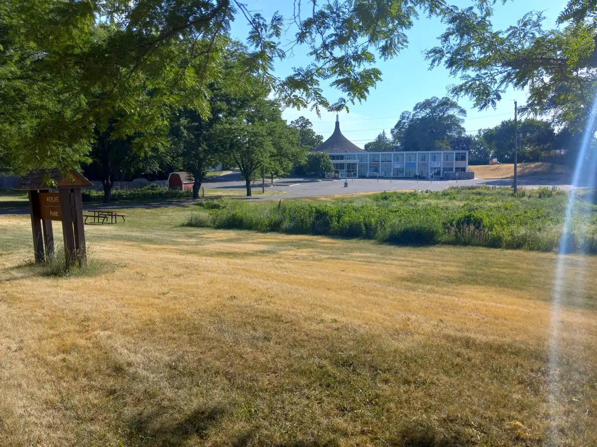 Mown park lawn, trees and a low recreation building at Mielke Park in Robbinsdale