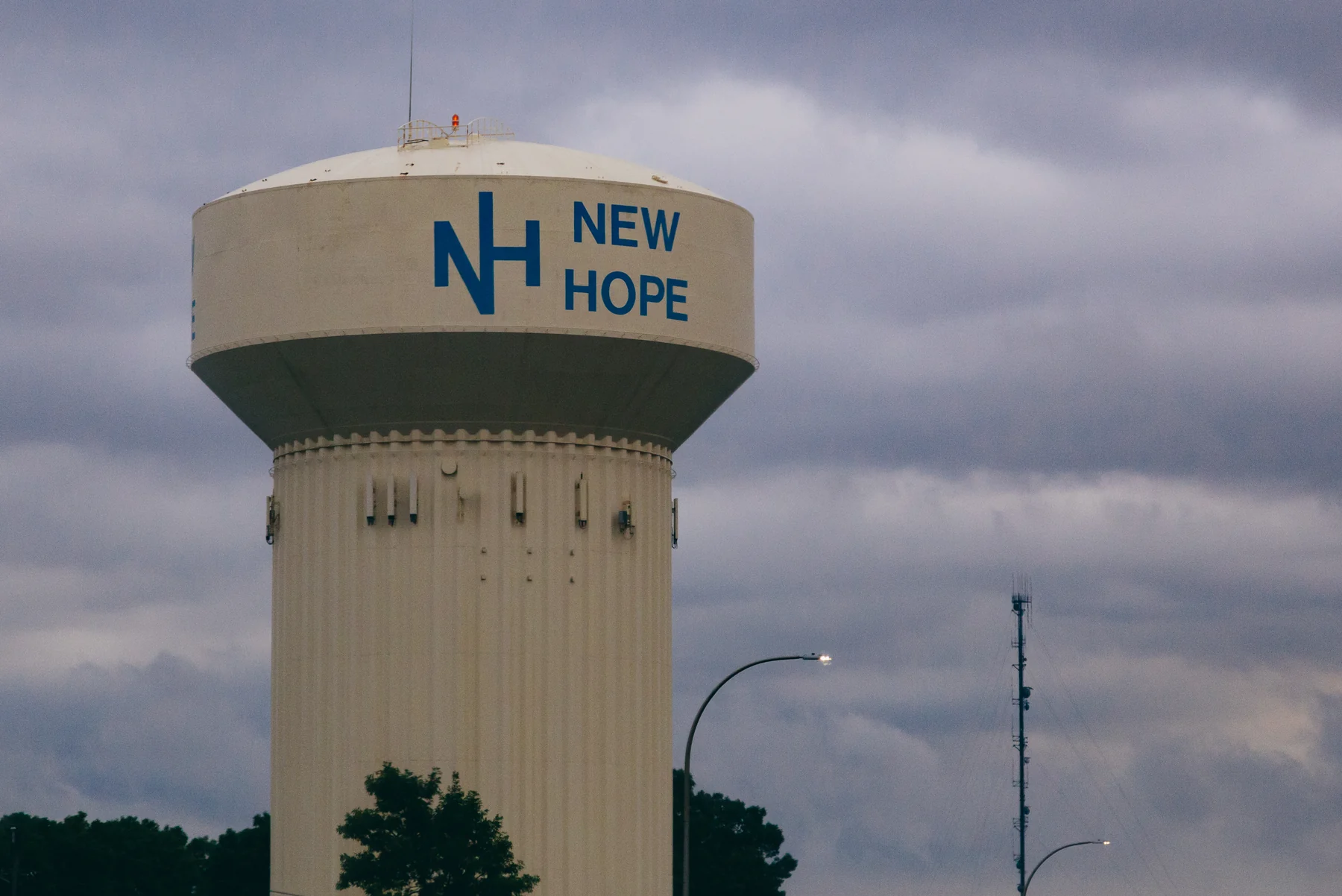 New Hope's white water tower with the city's NH logo against a gray sky