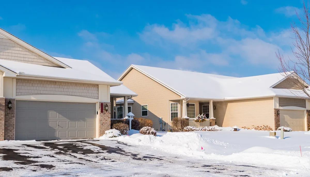 Newer suburban homes in Maple Grove, Minnesota, with lap and shake siding, white trim and brick piers after a fresh snow